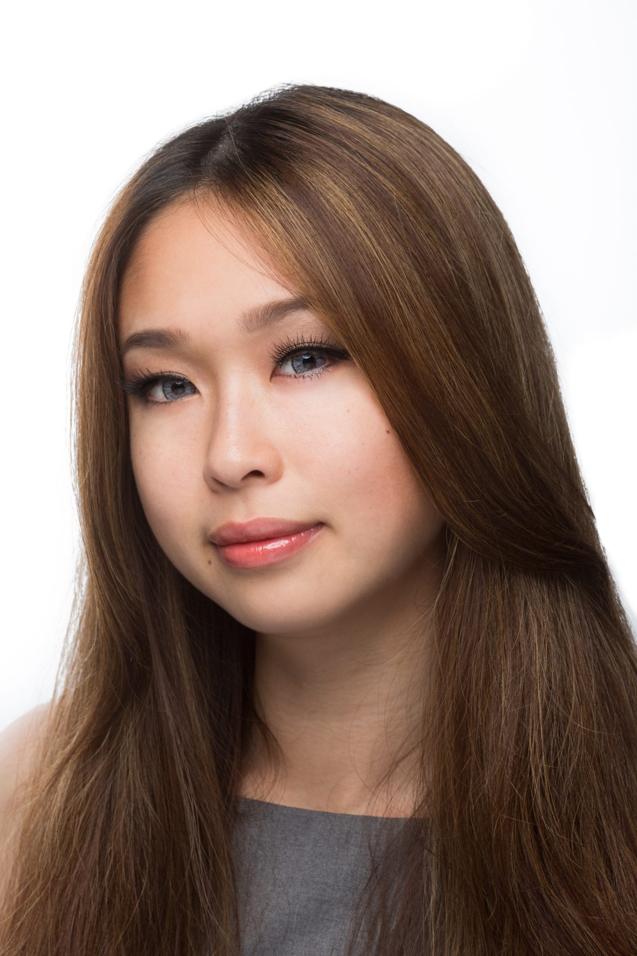 A person with long hair poses for a clean studio business headshot against a white background.