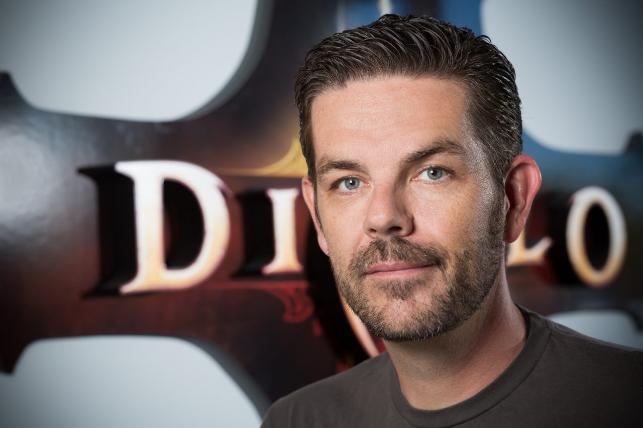 Professional Blizzard Entertainment staff headshot in front of a Diablo-themed backdrop.